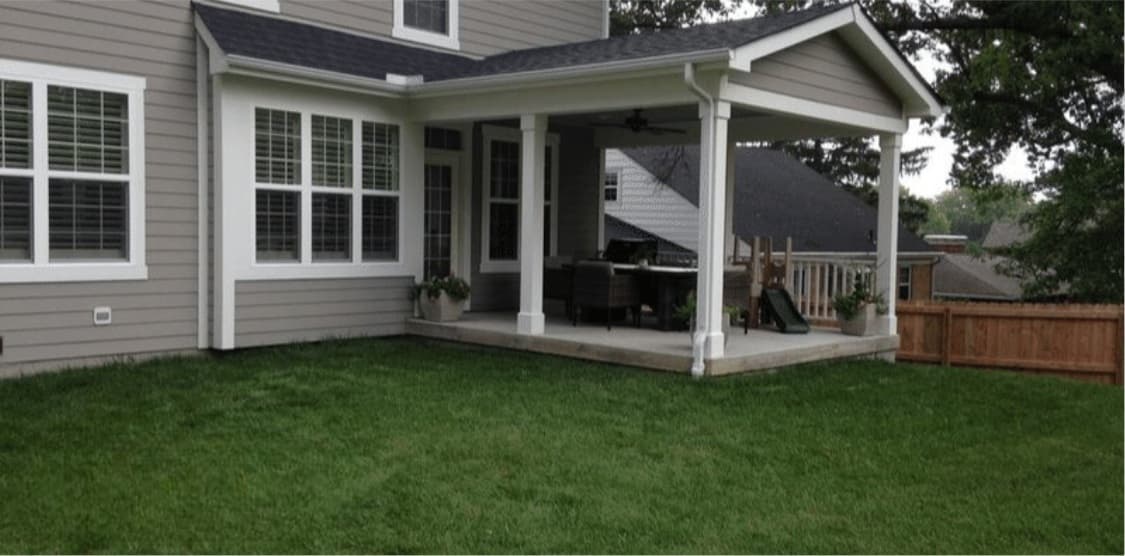 Backyard before hardscaping — plain concrete slab beneath the covered porch